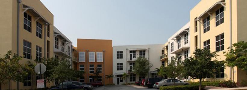 Front view of two-story, beige, pale yellow, and orange apartment buildings attached to each other forming a 